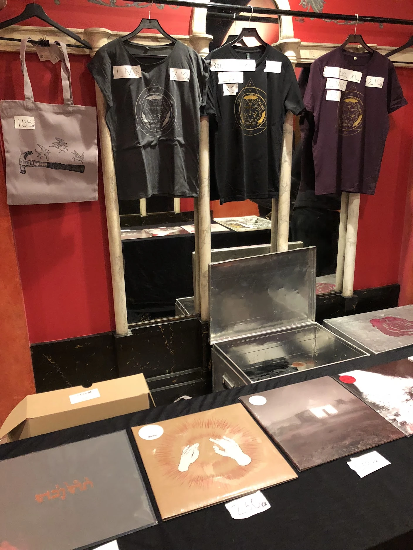 Vinyl records and T-shirts laid out on a band's merch table at a gig